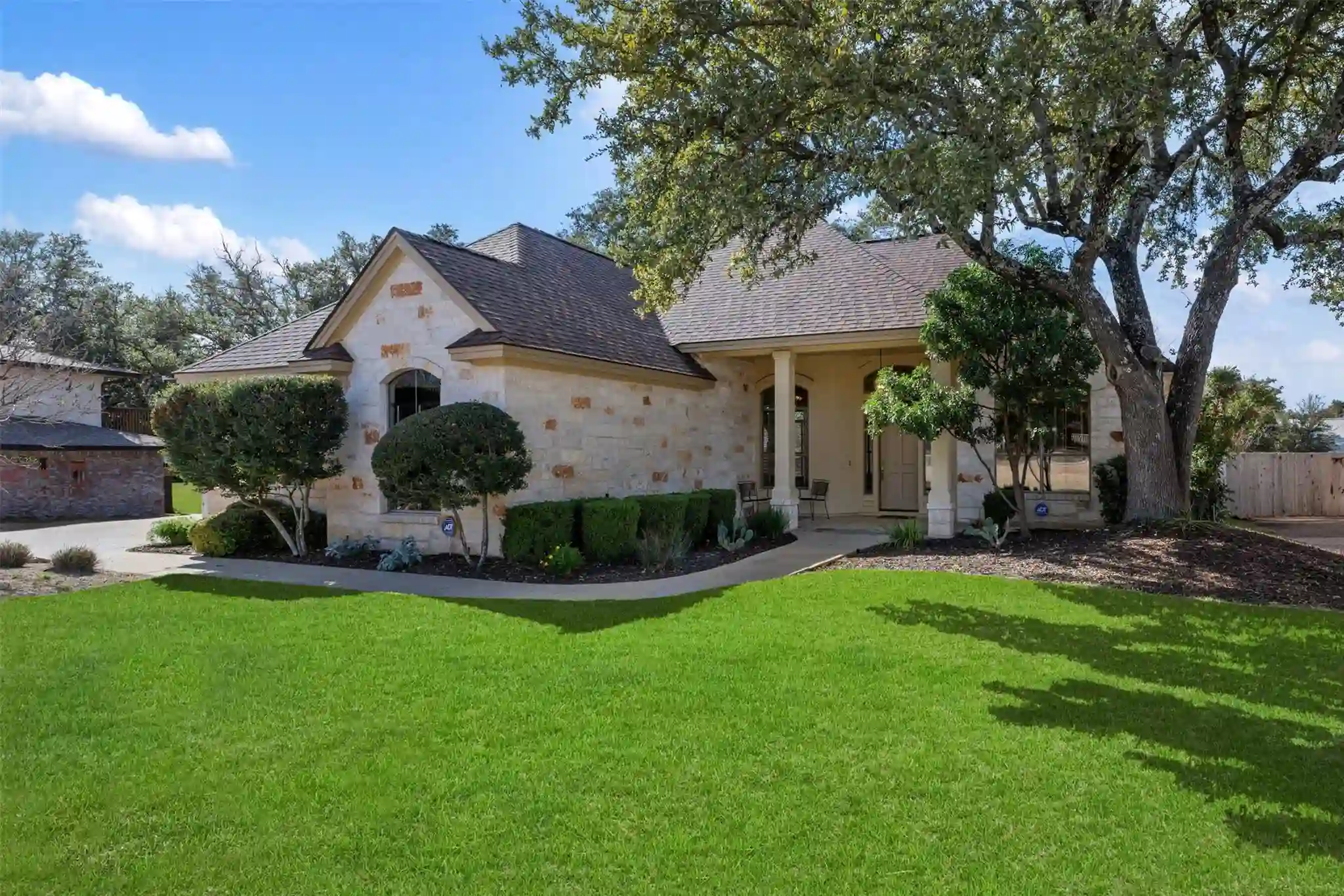 Lakeway Copperleaf Homestead assisted living home exterior with limestone facade, mature oak trees, and manicured lawn in Lakeway, TX